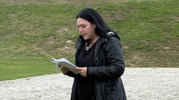 Eine junge Frau steht draußen und trägt etwas vor.