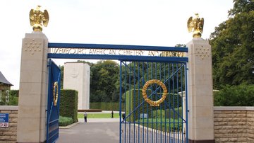 Ein blau-goldenes Tor mit goldenen Adlern auf den Torpfosten führt zur amerikanischen Kriegsgräberstätte