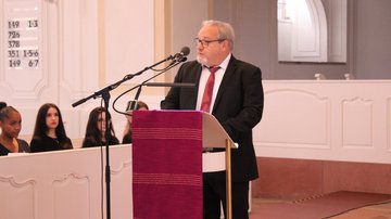 Ein Mann im Anzug spricht in einer Kirche am Mikrofon.