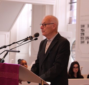 Ein Mann im Anzug spricht am Mikrofon in einer Kirche.