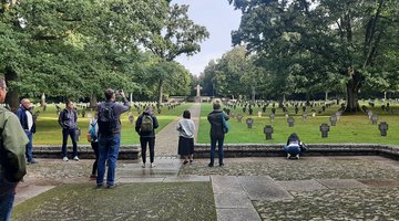 Eine kleine Gruppe Menschen fotografiert eine Kriegsgräberstätte