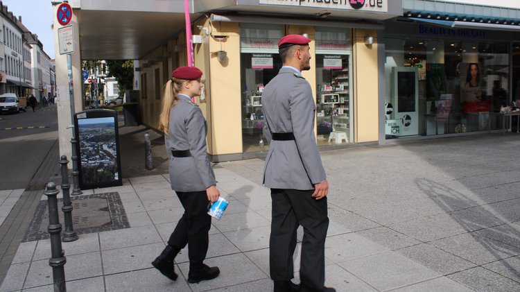 Eine Soldatin und ein Soldat gehen mit Sammeldose durch die Stadt.