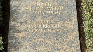 Eine verschmutzte Grabplatte mit Namen und Lebensdaten zweier Gefallener