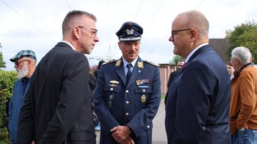 Drei Männer unterhalten sich. Einer trägt eine Luftwaffenuniform der Bundeswehr.