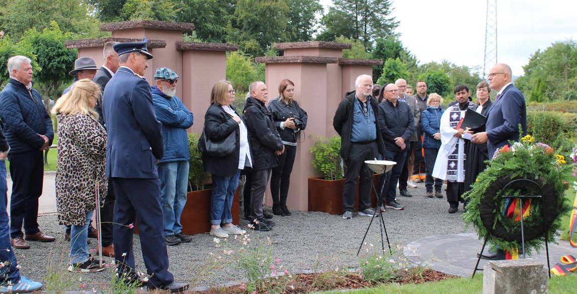 Eine Gruppe Menschen steht auf einem Friedhof.