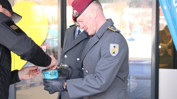 Zwei Soldaten mit einer Sammeldose, in die jemand Geld wirft