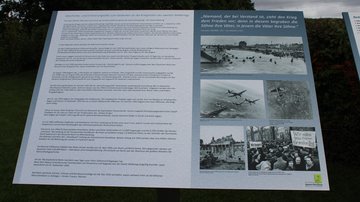 Eine Infotafel auf einer Kriegsgräberstätte informiert über den Zweiten Weltkrieg.